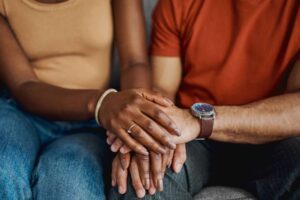 Two people comforting each other on a couch.