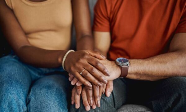 Two people comforting each other on a couch.