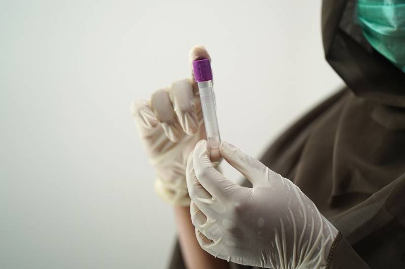 A lab worker holding a vial of blood