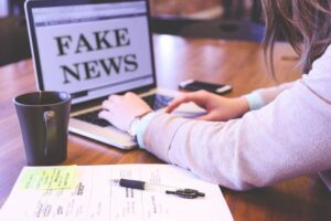 person typing on laptop whose screen reads "Fake News"