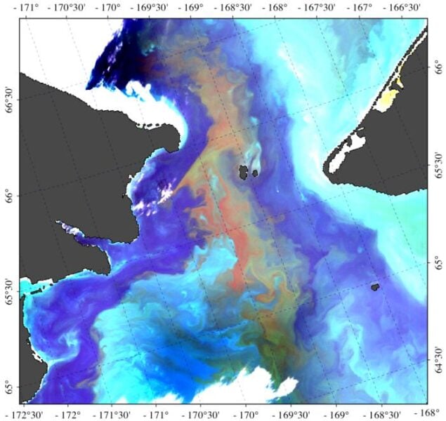 A satellite image of the Bering Strait, taken August 2, 2022, with presence of the Alexandrium bloom appearing in red.