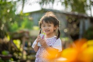 Happy girl in a field with a juice box