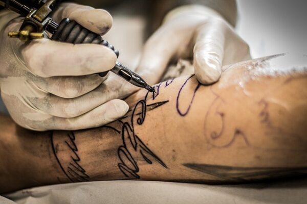 Tattoo artist at work on a man's arm