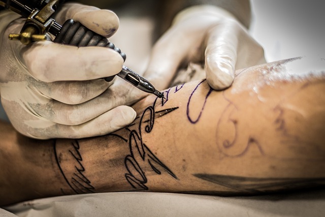 Tattoo artist at work on a man's arm