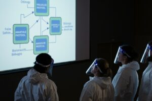 Researchers in protective gear look at a display on AI security