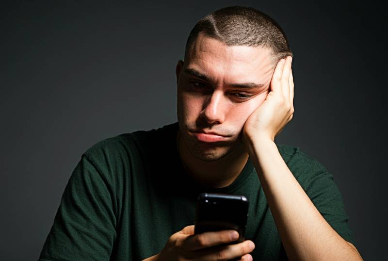 bored man looking at cell phone