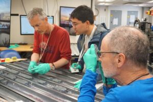 Caption: Professor Johan Lissenberg (left) and colleagues analysing the cores, which were recovered from a “tectonic window” on the Mid-Atlantic Ridge.