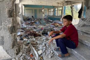 Boy sitting in the rubble of a destroyed UNRWA school in Nuseirat, Middle Areas of the Gaza Strip.