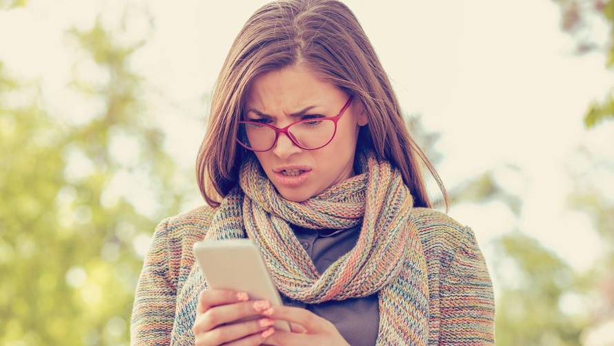 woman looks angrily at phone