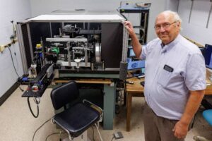 Stephen Burns stands with a high-precision ophthalmoscope capable of observing microscopic details in the back of the eye without distortion based on technology advanced at IU. Photo by Chris Meyer, Indiana University