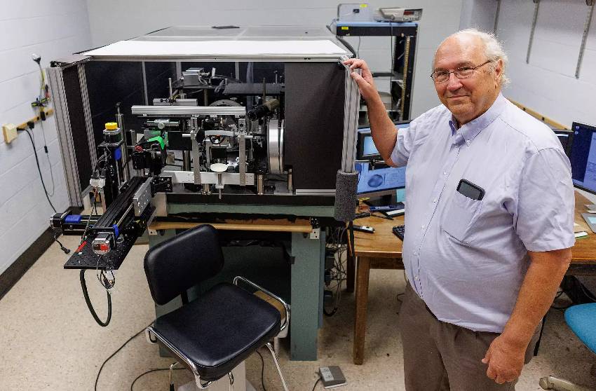 Stephen Burns stands with a high-precision ophthalmoscope capable of observing microscopic details in the back of the eye without distortion based on technology advanced at IU. Photo by Chris Meyer, Indiana University