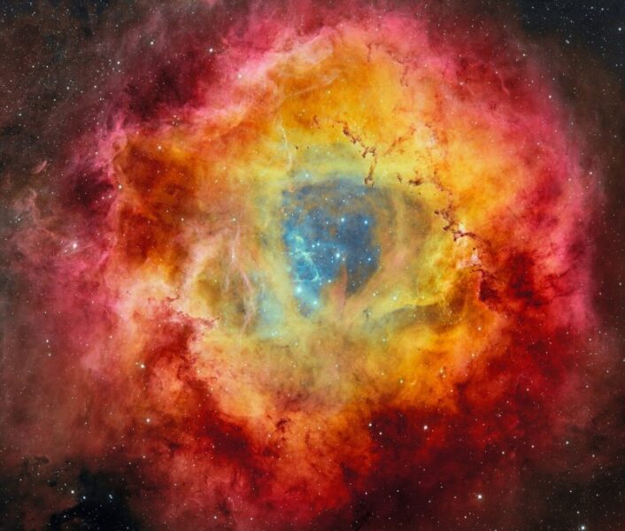 Cradled within the fiery petals of the Rosette Nebula is NGC 2244, the young star cluster which it nurtured. The cluster’s stars light up the nebula in vibrant hues of red, gold and purple, and opaque towers of dust rise from the billowing clouds around its excavated core. This image, captured by 570-megapixel Department of Energy-fabricated Dark Energy Camera (DECam), mounted on the U.S. National Science Foundation Víctor M. Blanco 4-meter Telescope at Cerro Tololo Inter-American Observatory, a Program of NSF NOIRLab, is being released in celebration of NOIRLab’s fifth anniversary.