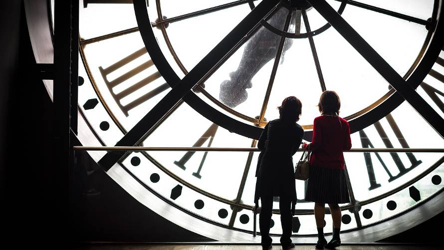 two women behind an enormous clock