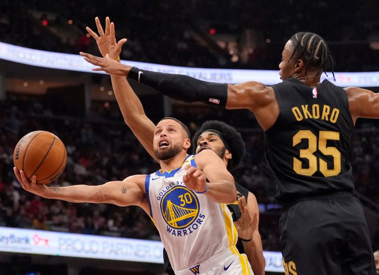 Golden State Warriors guard Stephen Curry goes to the basket in front of Cleveland Cavaliers center Jarrett Allen, rear, and forward Isaac Okoro in the first half of an NBA basketball game on Friday, Nov. 8, 2024, in Cleveland. (AP Photo/Sue Ogrocki)