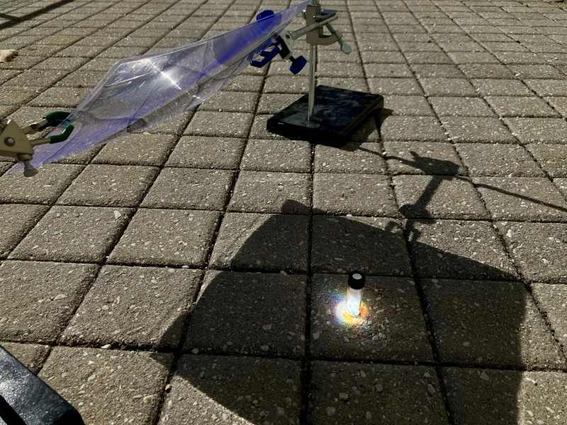 Inside this reaction vial, spotlit by concentrated sunlight, a piece of black polystyrene from a foam tray breaks down into a recyclable material.