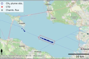 Dashed blue lines show shipping lanes, and dark blue circles mark CH₄ plumes. The sampled area (5.46 km × 0.12 km; 0.66 km²) is outlined by a red dashed box. The CTD profile site is marked by a red star, chamber flux measurements by a black cross, and the flood-protection dam by a solid red line spanning the bay via Kotlin Island.
