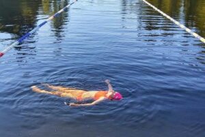 swimmer floating on her back in a laned pool in a lake