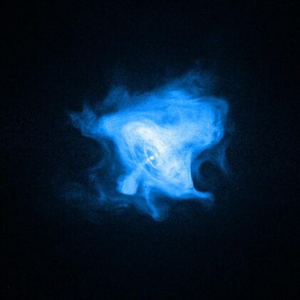 In the Crab Nebula, a rapidly spinning neutron star, or pulsar (white dot near center), drives the activity seen by Chandra. Its inner X-ray ring marks a shock wave where the pulsar wind meets the surrounding nebula. Energetic matter and antimatter flow outward, forming jets from the poles and bright outer rings, while magnetic forces sculpt the nebula’s outer fingers, loops, and bays.