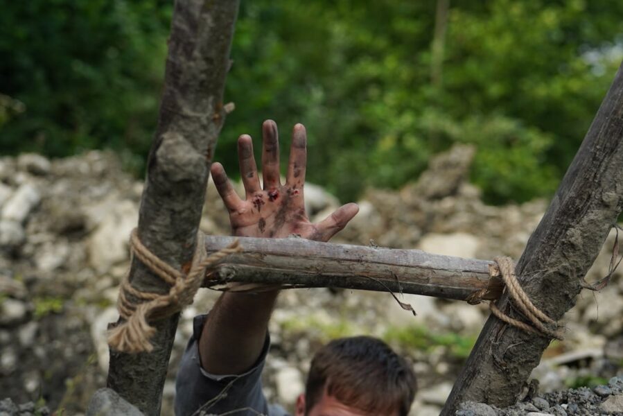 wounded man reaches up for help