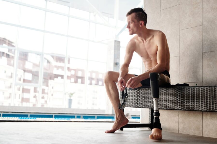 Man with prosthetic lower leg in swim suit near a pool