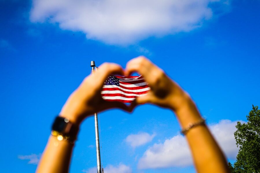 two hands outlining a heart over a U.S. flag