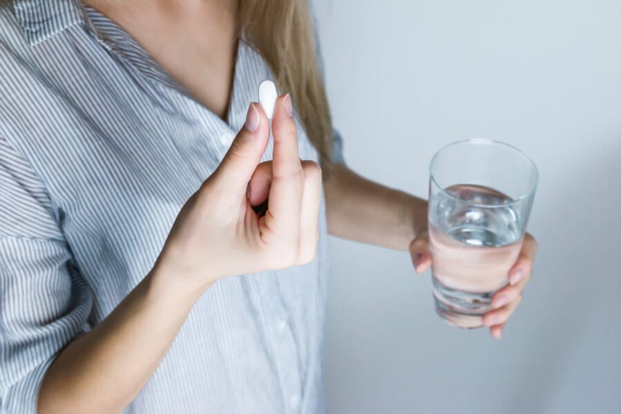 woman taking pill with glass of water