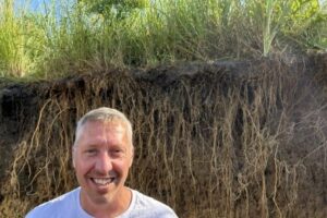 Iowa State University researcher Cole Dutter in a soil pit next to a prairie strip.
