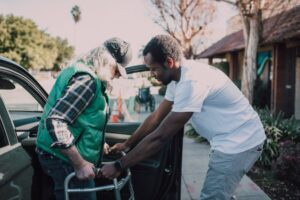 younger man helping a senior with a walker
