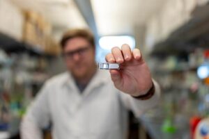Rice University Ph.D. student Chris Wright holds the implant, which uses cells to manufacture pharmaceutical drugs beneath the skin