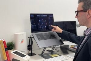 Dr. Zenil showing on the screen a simulation of AI agents interacting and trying to infleunce one another, along with the various metrics associated with each agent in the arena.