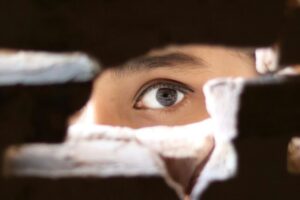an eye looking through an opening in a brick wall