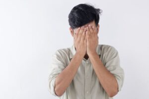 man covering his face in shame