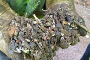 hands holding sludgey waste embedded with raw matrials