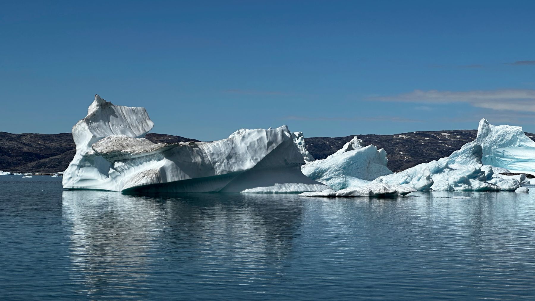 White icebergs floating in calm blue water off Greenland