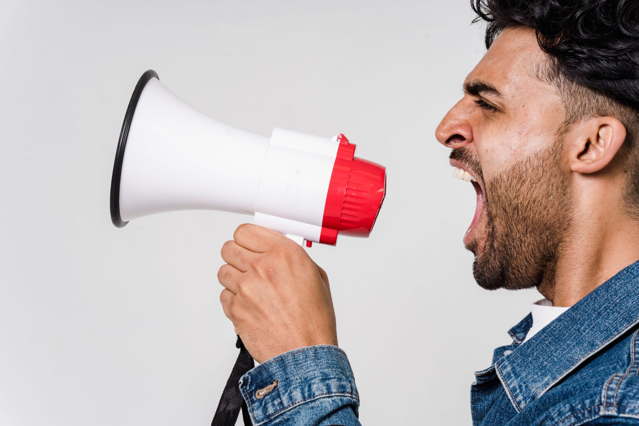 A man shouting into a megaphone with a passionate expression, a representative image and not a photograph of any person discussed in the article.