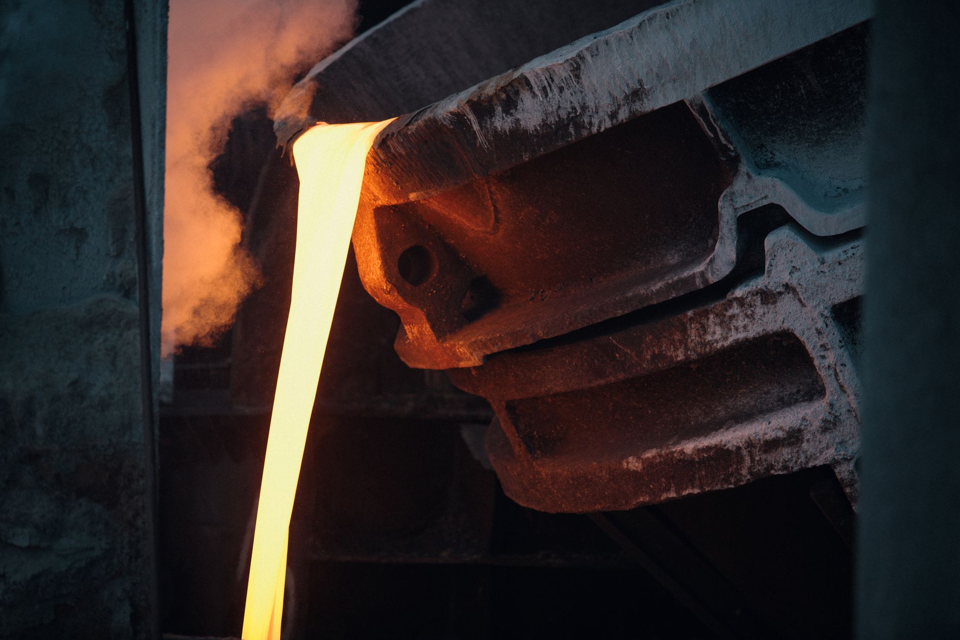Bright molten metal pouring from a foundry ladle