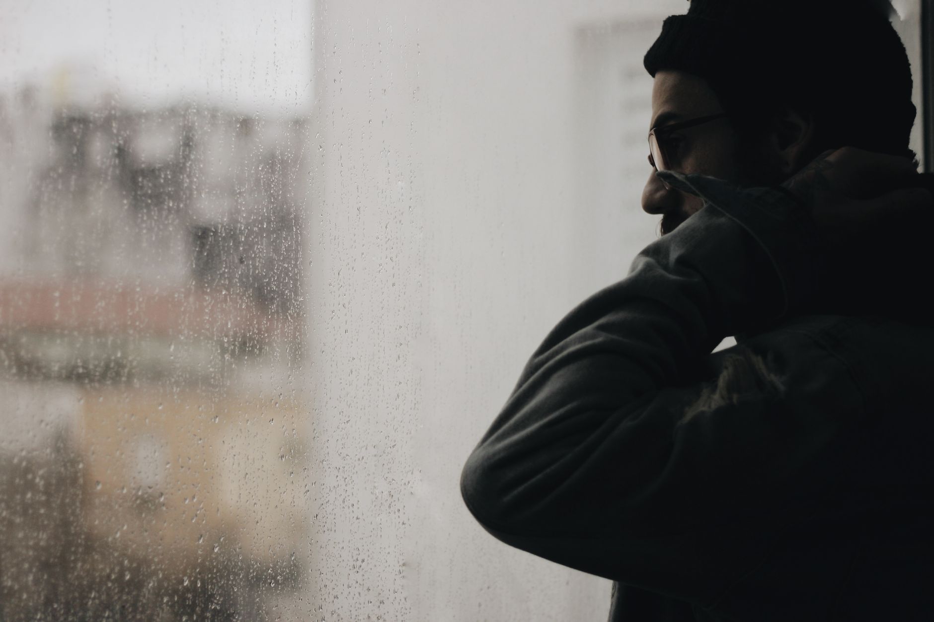 A person looking out through a rain-covered window