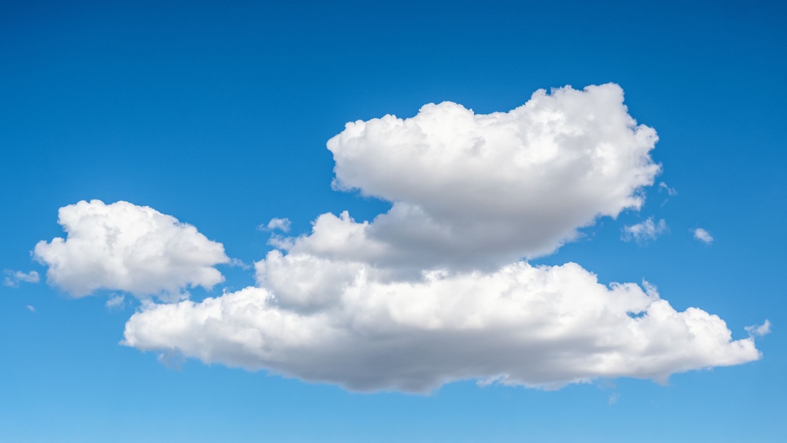 Large fluffy white cumulus clouds against a clear blue sky
