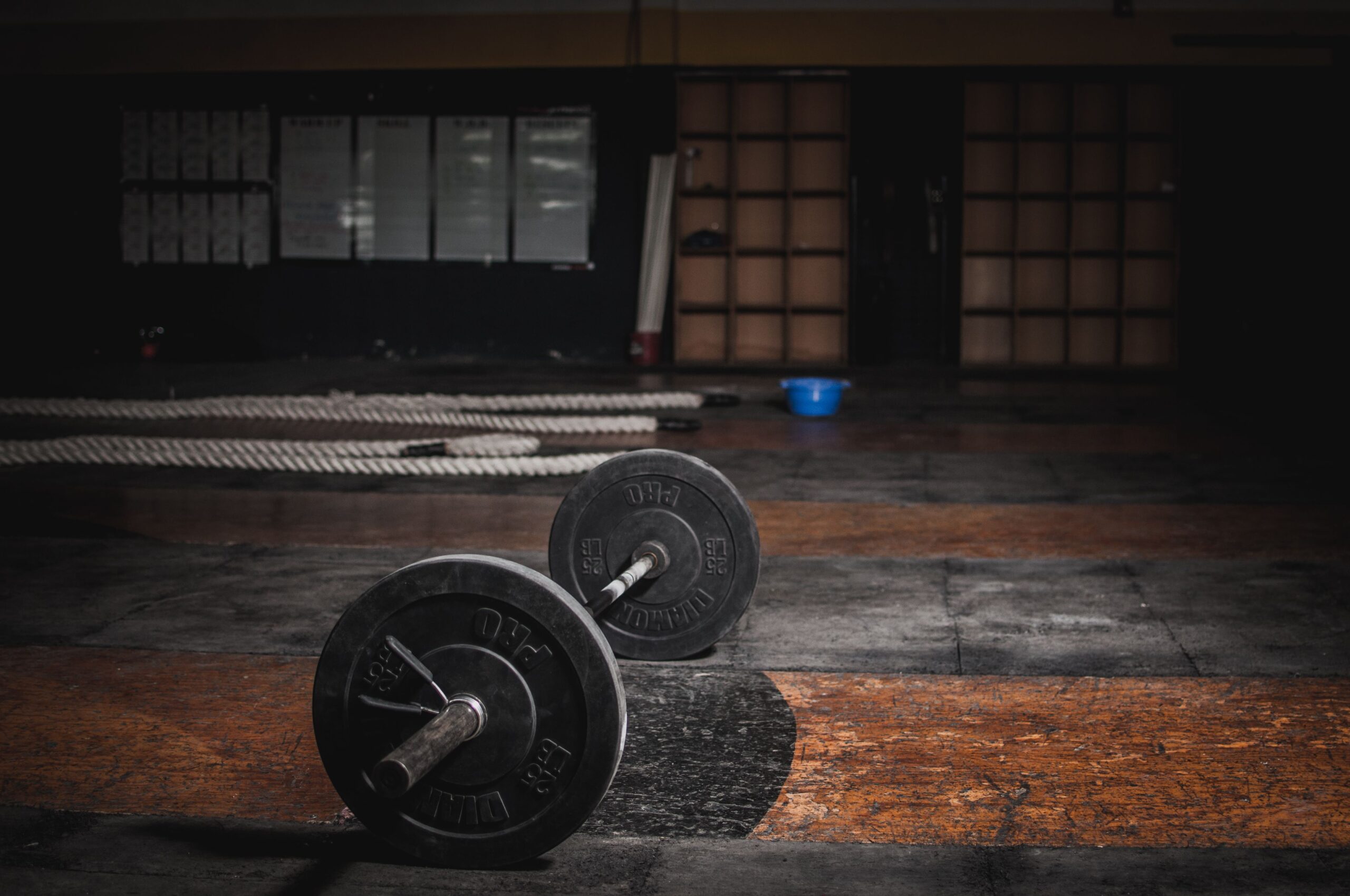 Barbells resting on the floor of a quiet, empty gym