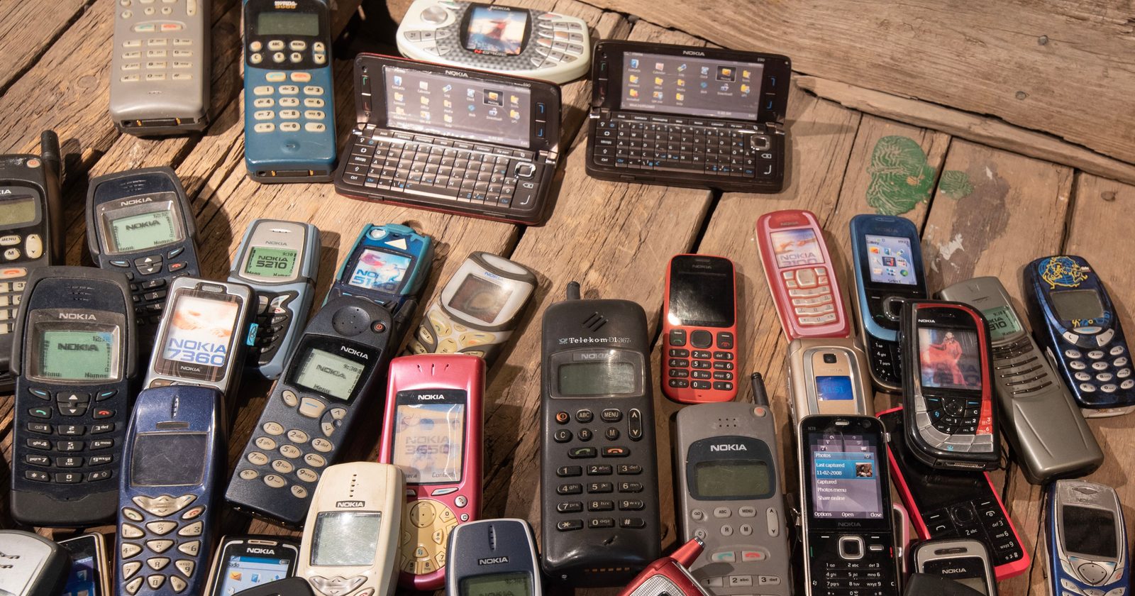 An assortment of retro mobile phones displayed on a rustic wooden surface, showcasing nostalgia.