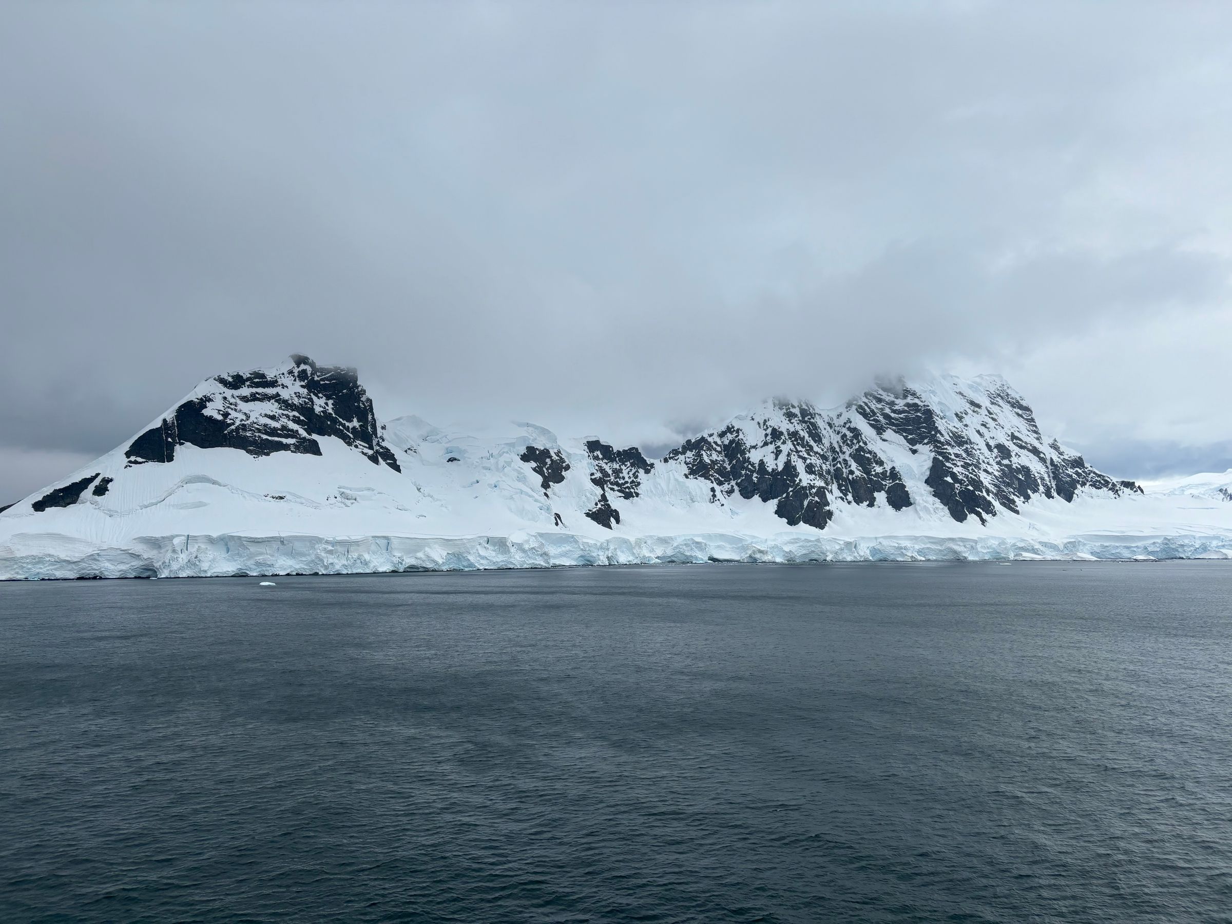 Snow-covered Antarctic mountains above an icy coastline