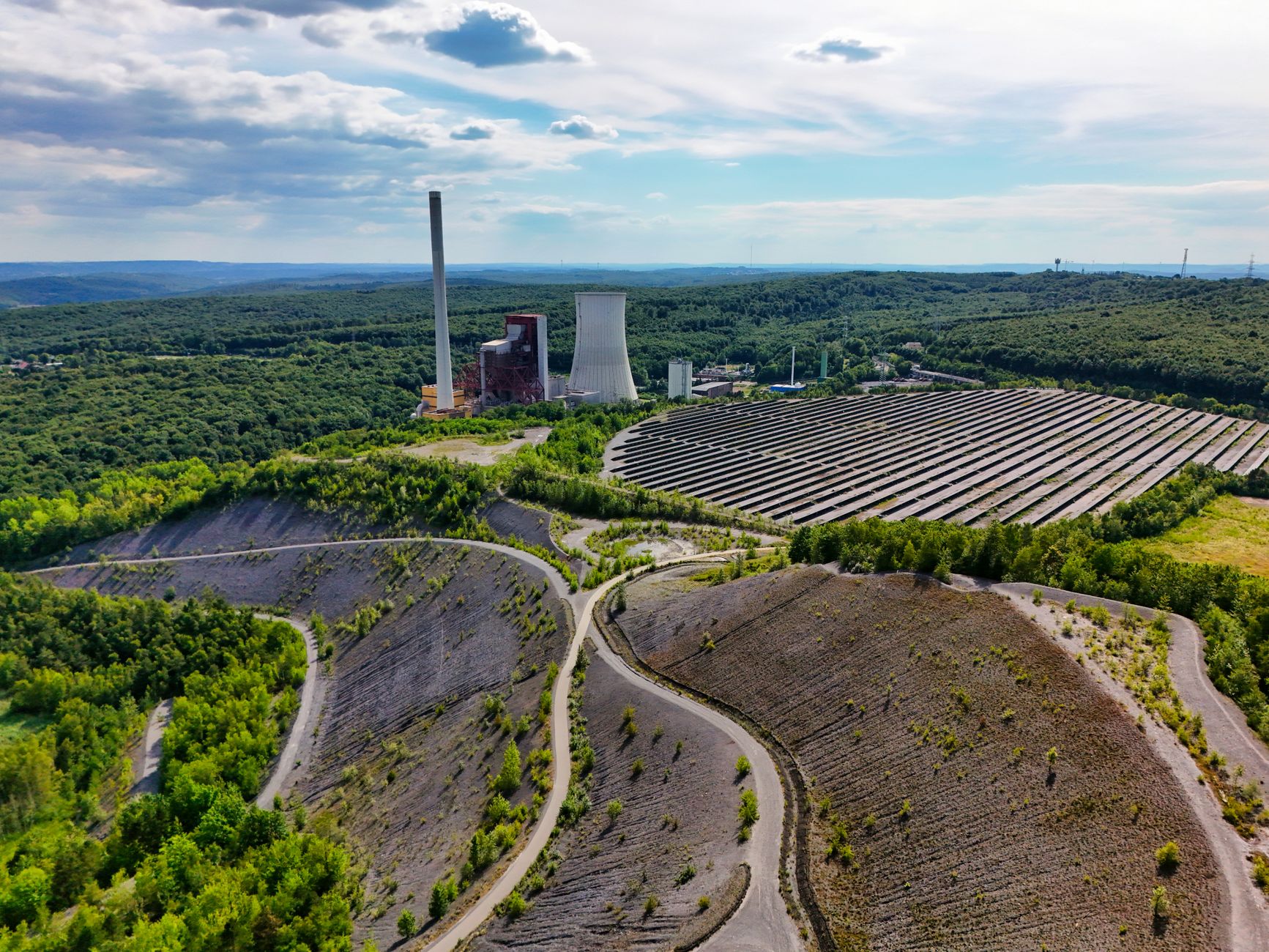 A large solar farm beside an older industrial power plant