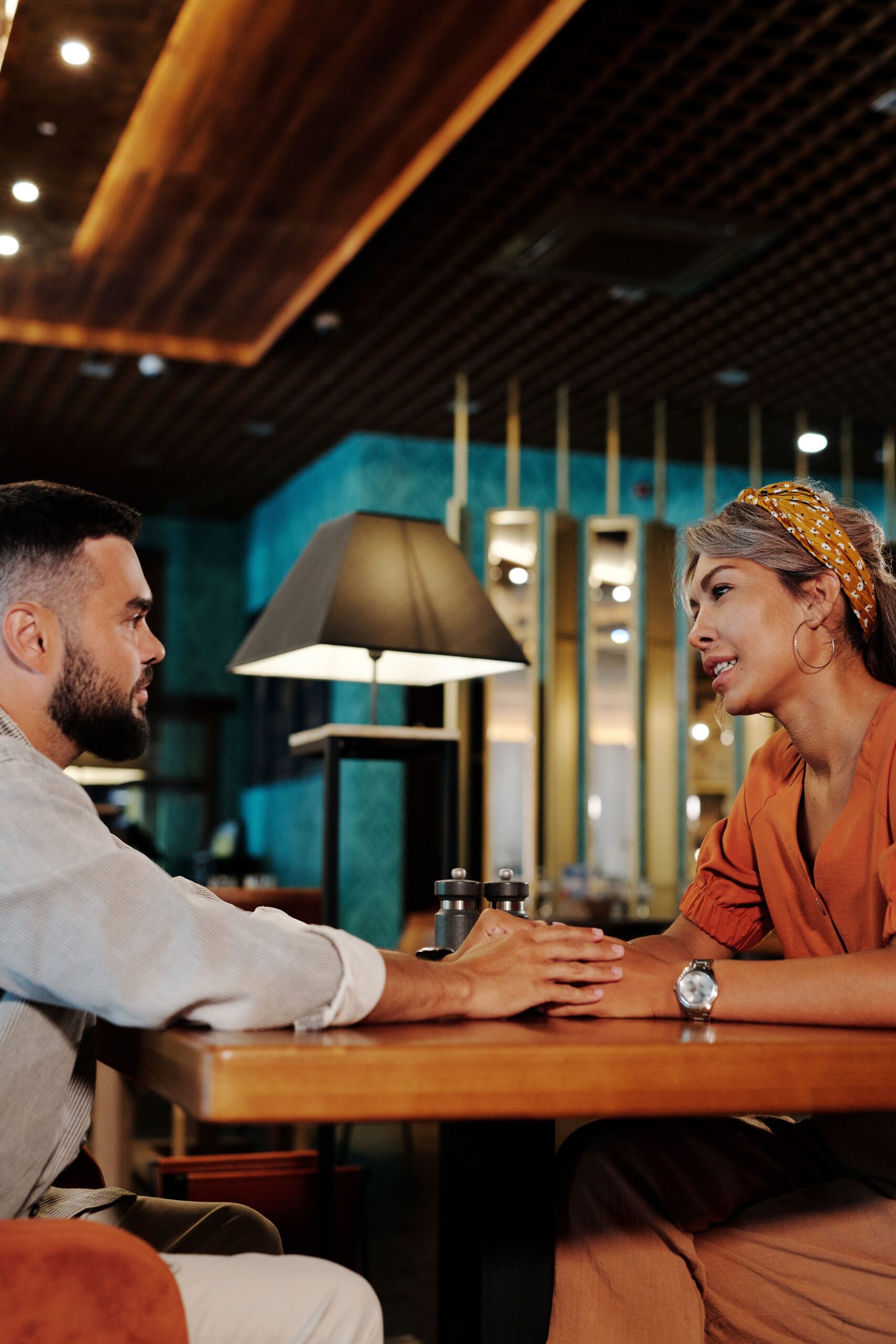 A man and woman in conversation across a table at a bar