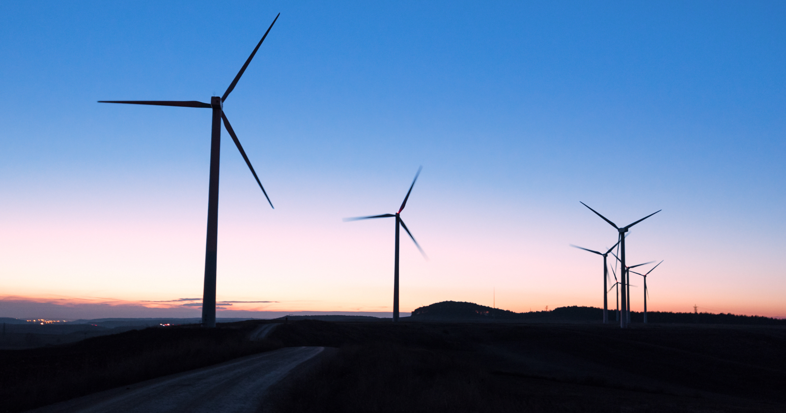 Wind turbines beside a road at dusk