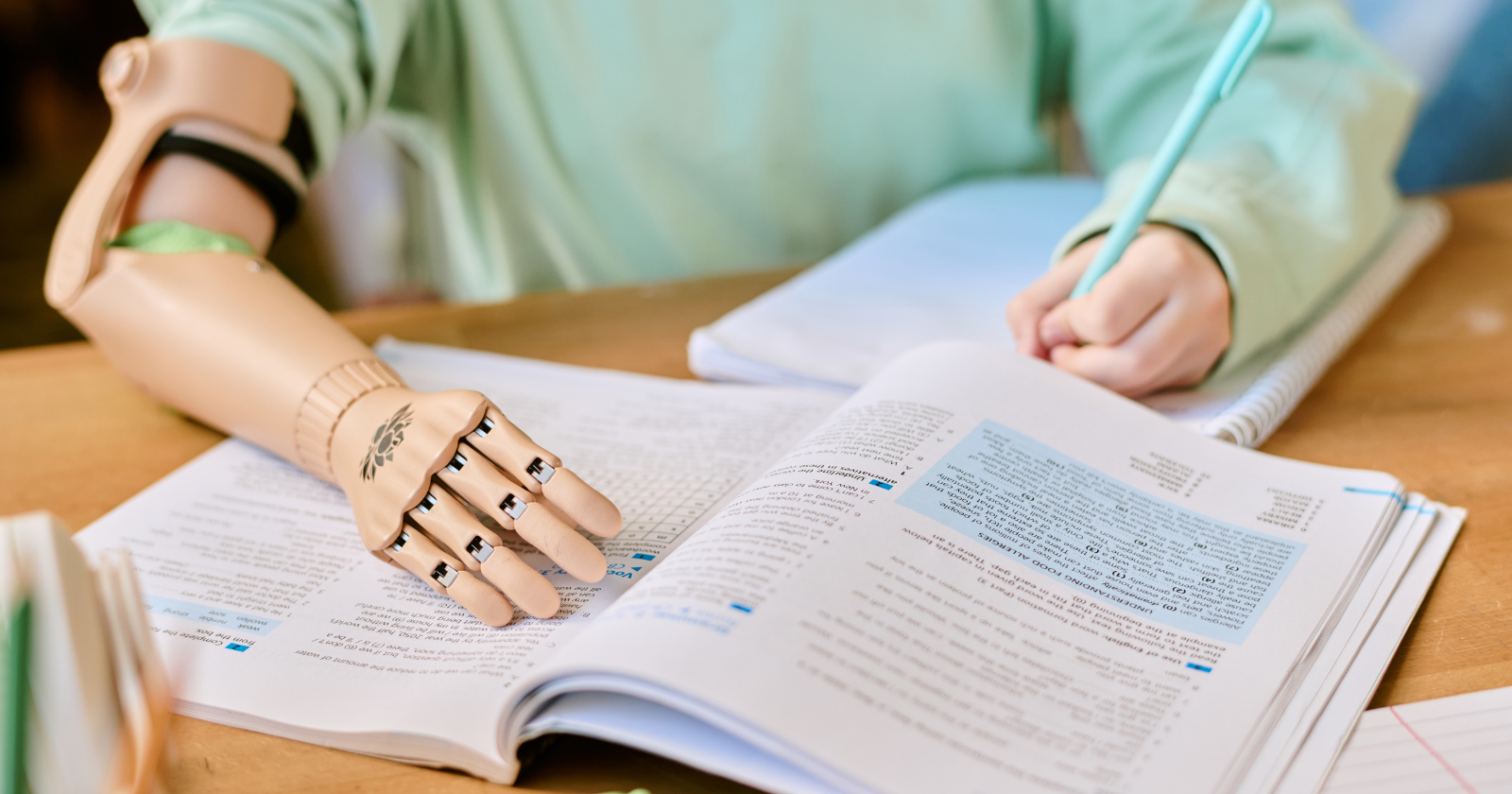 Person with a prosthetic hand writing in a workbook