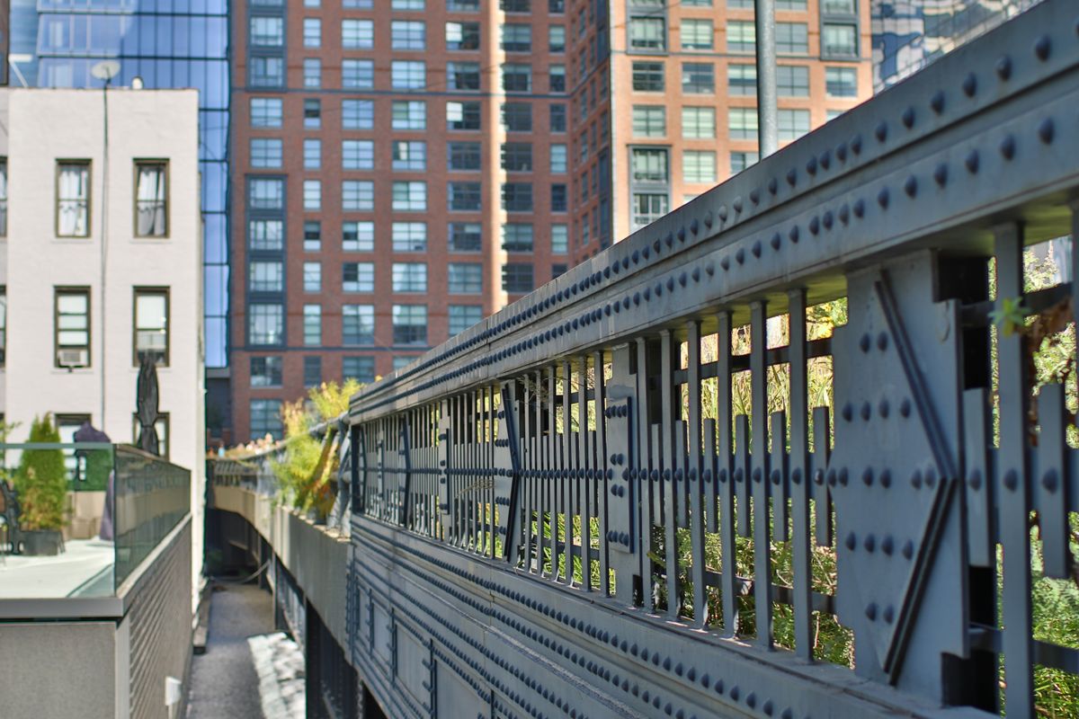 Steel railing and planting along the High Line with Manhattan buildings behind it