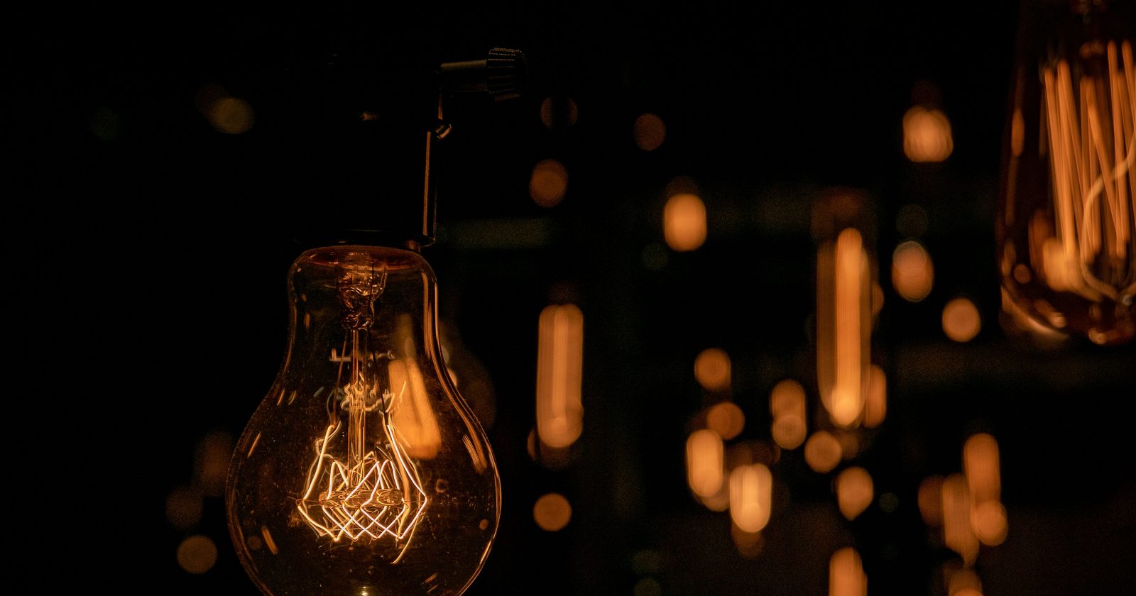 Warm glow of vintage light bulbs hanging in a dark setting, creating an inviting atmosphere.