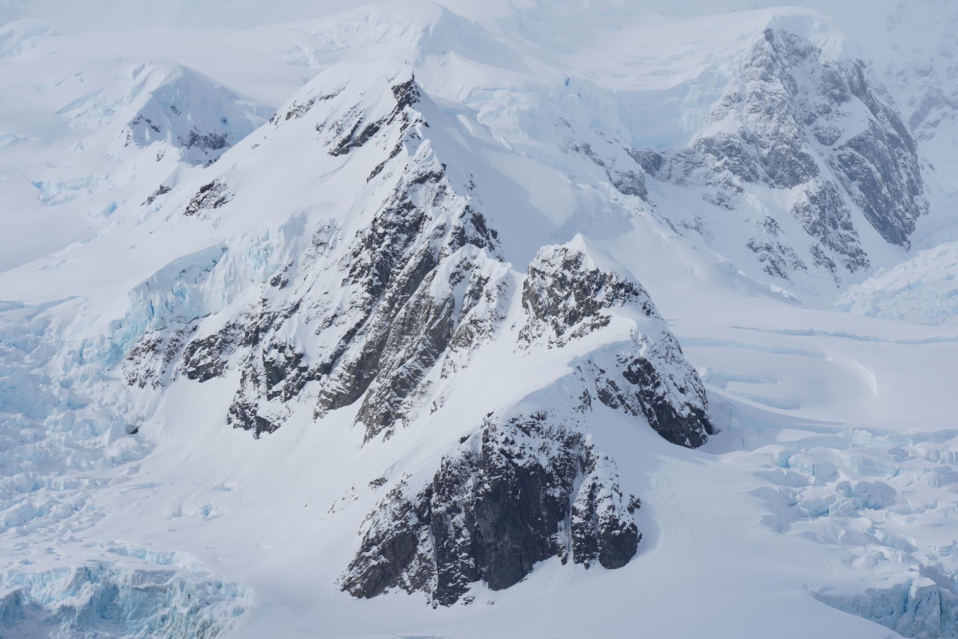 An aerial view across snow-covered mountains and glaciers in Antarctica