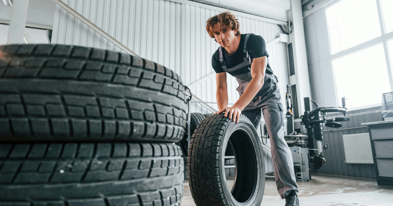 Worker moving a large tyre in a garage