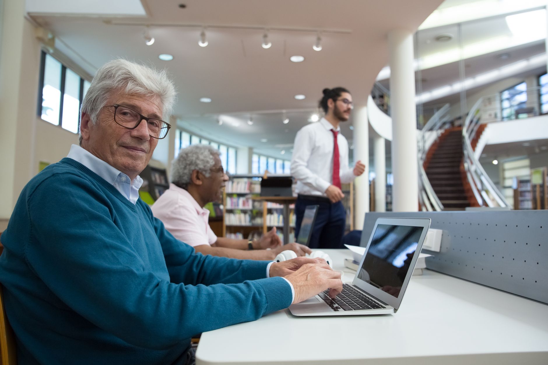 Older man using a laptop at a library table